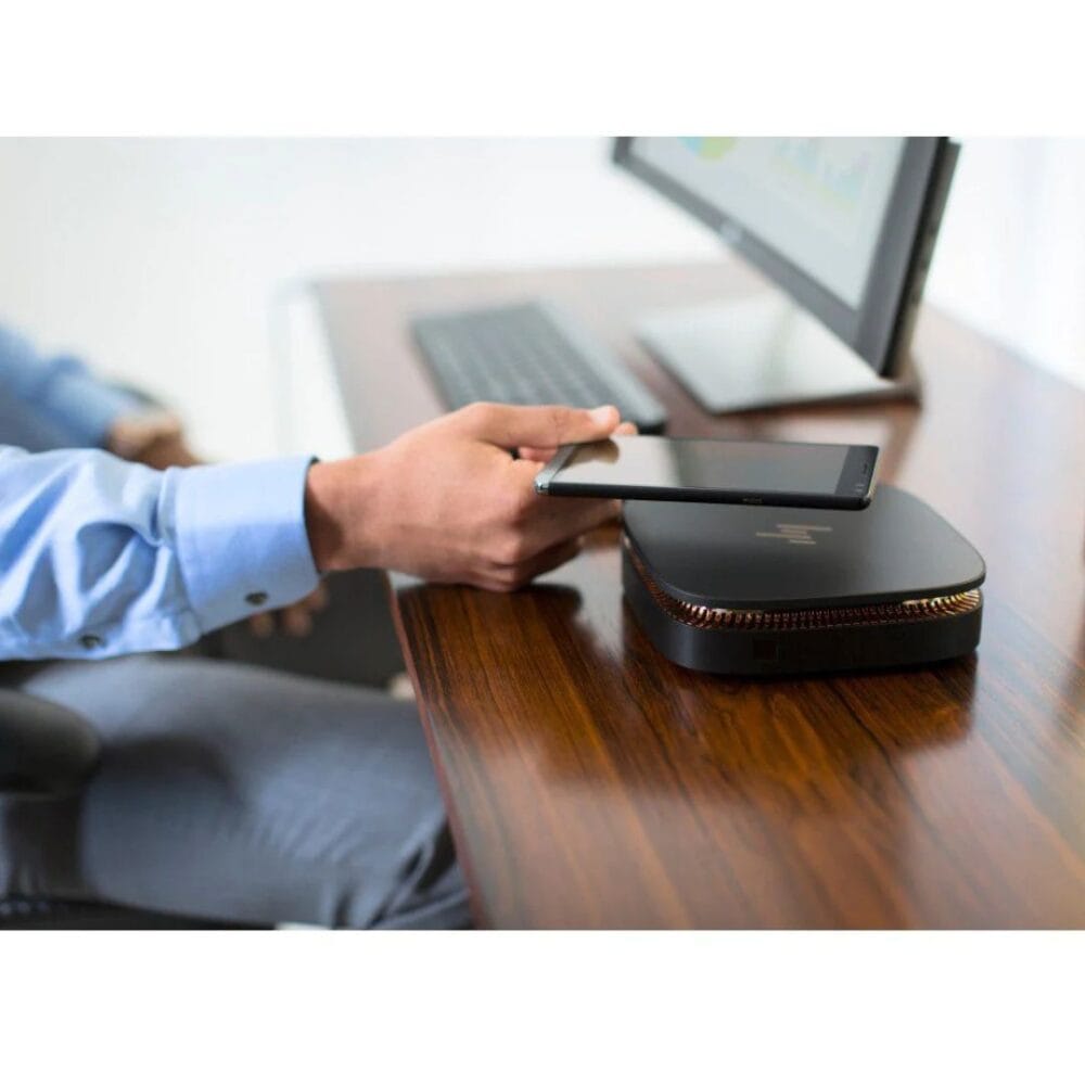 Postazione HP Mini PC Slice, mano che tiene uno smartphone vicino al pc e al monitor su una scrivania