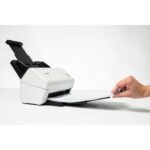 Scanner Desktop Brother ADS4300N, con mano che prende i fogli